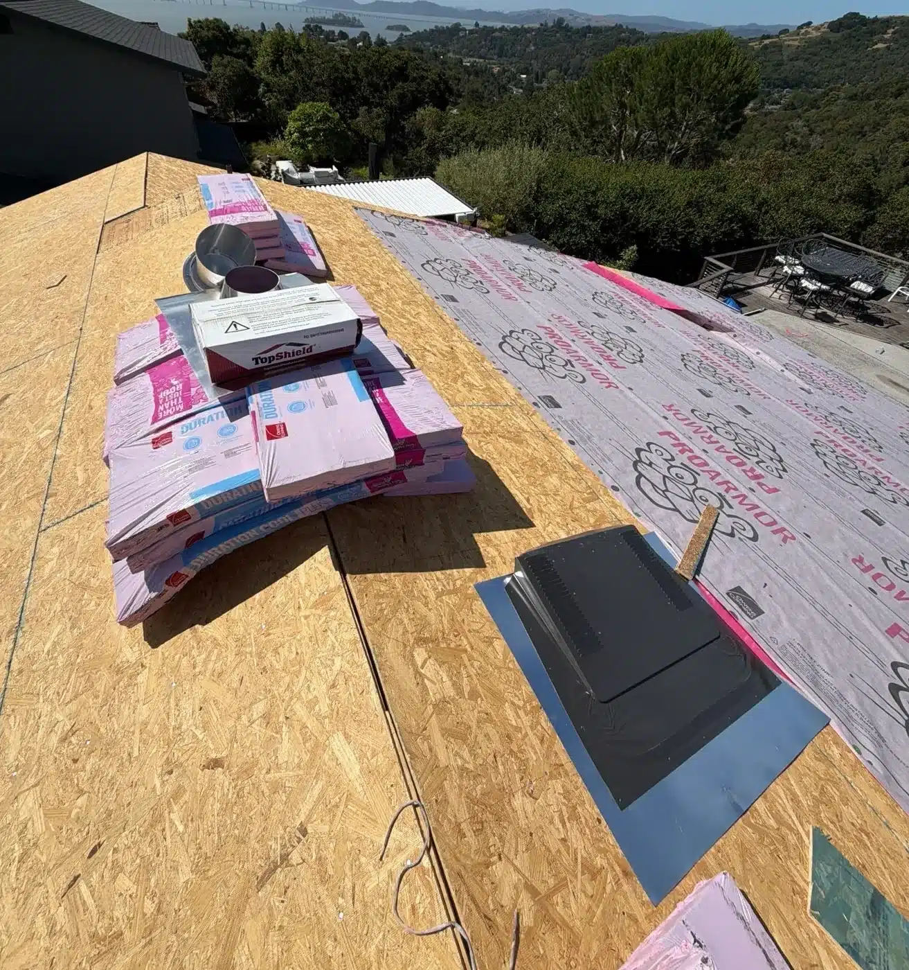 New OSB roof decking with synthetic underlayment rolls and Owens Corning Duration COOL shingle bundles staged on the San Rafael reroof