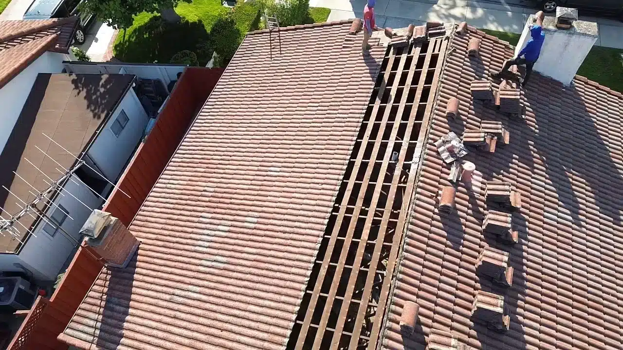 First rows of concrete tile lifted on a San Mateo roof, exposing the original spaced board sheathing