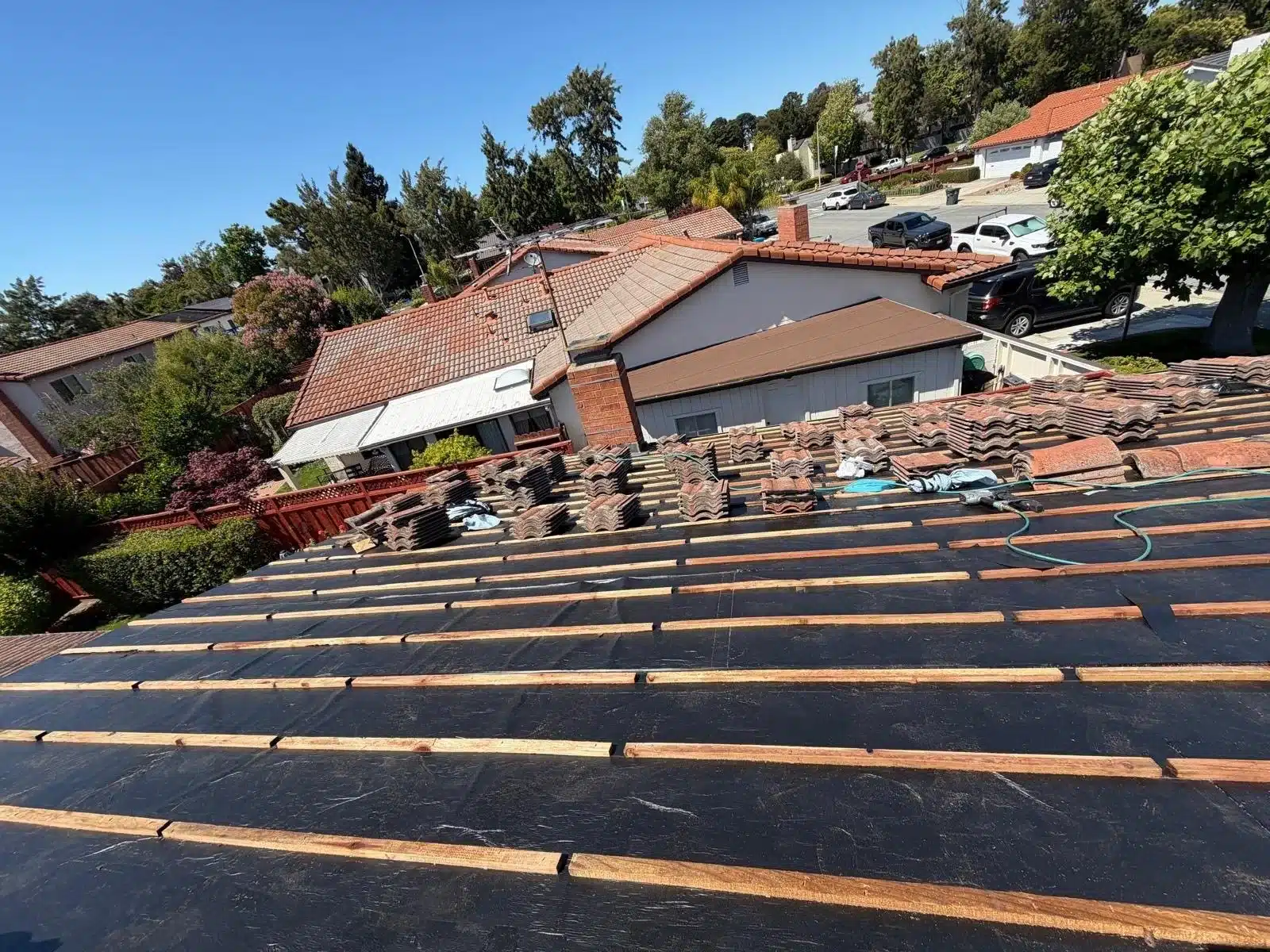 Original concrete tiles stacked on new underlayment and battens, ready to be relaid on a San Mateo roof